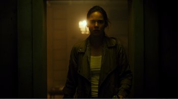 Movie still from “Rings” (2017), directed by F. Javier Gutiérrez – A woman standing in a dark room holding a cell phone; Medium shot, Low angle