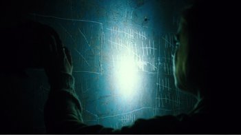 Movie still from “Rings” (2017), directed by F. Javier Gutiérrez – A person looking at a wall with a light shining on it; Close Up shot, Over the shoulder angle
