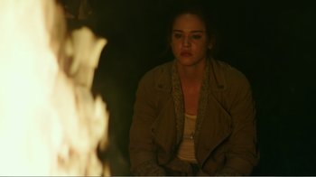 Movie still from “Rings” (2017), directed by F. Javier Gutiérrez – A woman sitting in front of a fire in the dark; Medium shot, High angle