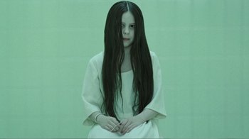 Movie still from “Rings” (2017), directed by F. Javier Gutiérrez – A woman with long black hair sitting in a room; Medium shot, High angle
