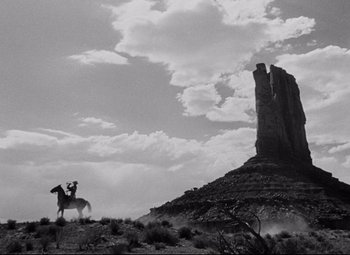 Movie still from “Rio Grande” (1950), directed by John Ford – A man on a horse in the middle of the desert; Extreme Wide shot, Low angle