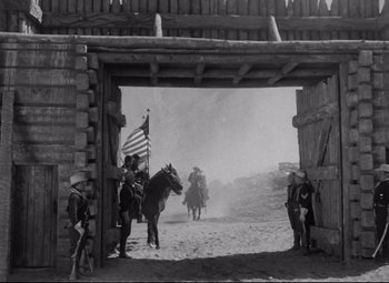 Movie still from “Rio Grande” (1950), directed by John Ford – An old photo of men on horses in a dirt field; Wide shot, Low angle