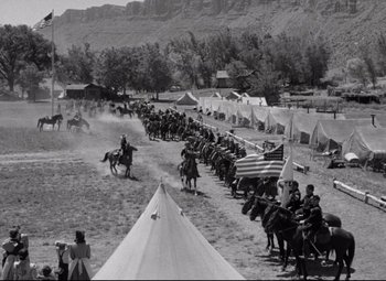 Movie still from “Rio Grande” (1950), directed by John Ford – A black and white photo of a group of men on horses; Extreme Wide shot, High angle