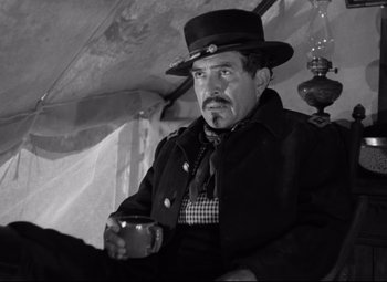 Movie still from “Rio Grande” (1950), directed by John Ford – A black and white photo of a man holding a coffee cup; Medium shot, Low angle