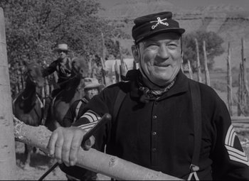 An older man holding a stick in front of another man