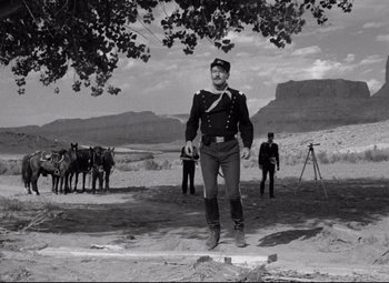 Movie still from “Rio Grande” (1950), directed by John Ford – A black and white photo of a man in a military uniform; Wide shot, Low angle