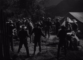 Movie still from “Rio Grande” (1950), directed by John Ford – A group of men standing next to each other in a field; Wide shot, High angle