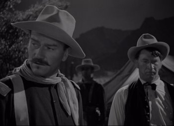 Movie still from “Rio Grande” (1950), directed by John Ford – A man in a cowboy hat standing next to another man in a cowboy hat; Medium shot, Low angle