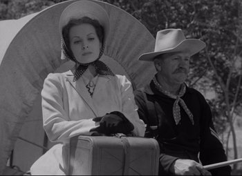 Movie still from “Rio Grande” (1950), directed by John Ford – An old photo of a man and a woman sitting on a bench; Medium shot, Low angle