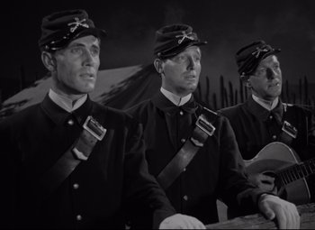 Movie still from “Rio Grande” (1950), directed by John Ford – A group of men standing next to each other in uniforms; Medium shot, Low angle