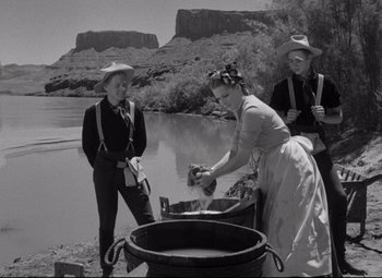 Movie still from “Rio Grande” (1950), directed by John Ford – Three people standing near a body of water; Wide shot, Low angle