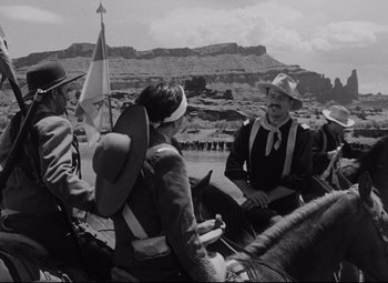A black and white photo of people on horses