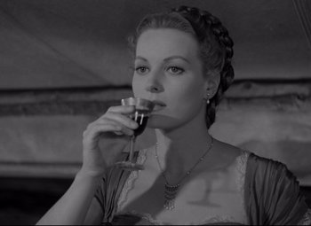 Movie still from “Rio Grande” (1950), directed by John Ford – A black and white photo of a woman drinking a glass of red wine; Close Up shot, Low angle