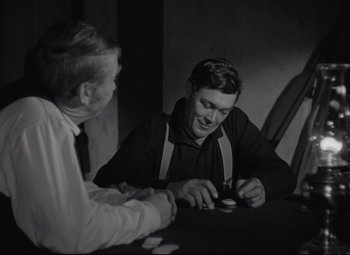 Movie still from “Rio Grande” (1950), directed by John Ford – Two men sitting at a table playing a card game; Medium shot, Over the shoulder angle