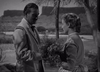 Movie still from “Rio Grande” (1950), directed by John Ford – An old photo of a man and a woman holding flowers; Medium shot, Over the shoulder angle
