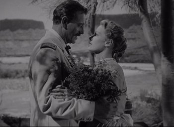 Movie still from “Rio Grande” (1950), directed by John Ford – An old photo of a man and a woman hugging; Medium shot, Low angle