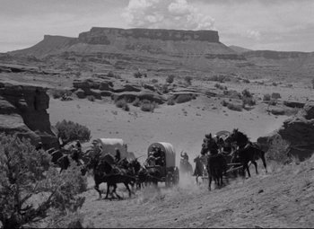 Movie still from “Rio Grande” (1950), directed by John Ford – A black and white photo of a wagon train in the wild west; Extreme Wide shot, High angle