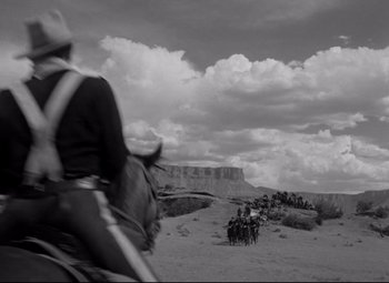 Movie still from “Rio Grande” (1950), directed by John Ford – A black and white photo of a group of people on horses; Wide shot, Low angle