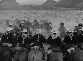 Movie still from “Rio Grande” (1950), directed by John Ford – A black and white photo of men on horses; Wide shot, Low angle