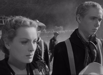 Movie still from “Rio Grande” (1950), directed by John Ford – A black - and - white photo of a woman and two men; Close Up shot, Over the shoulder angle