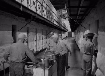 Movie still from “Riot in Cell Block 11” (1954), directed by Don Siegel – A black and white photo of men working in a kitchen; Wide shot, High angle