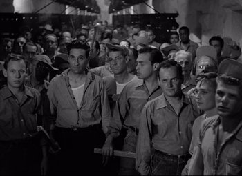 Movie still from “Riot in Cell Block 11” (1954), directed by Don Siegel – Black and white photograph of a group of men; Wide shot, High angle