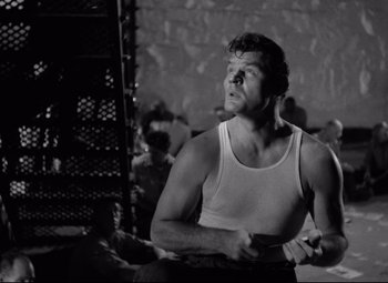 Movie still from “Riot in Cell Block 11” (1954), directed by Don Siegel – Black and white photograph of a man looking up; Medium shot, Low angle