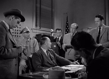 Movie still from “Riot in Cell Block 11” (1954), directed by Don Siegel – A group of men sitting around a table; Medium shot, Low angle