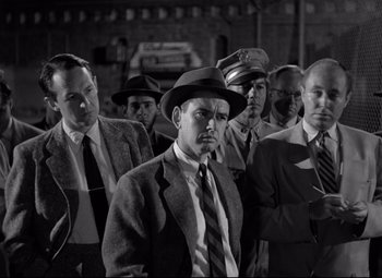 Movie still from “Riot in Cell Block 11” (1954), directed by Don Siegel – Black and white photograph of men in suits and hats; Medium shot, Low angle