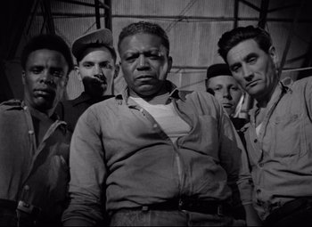 Movie still from “Riot in Cell Block 11” (1954), directed by Don Siegel – A black and white photo of a group of men; Medium shot, Low angle