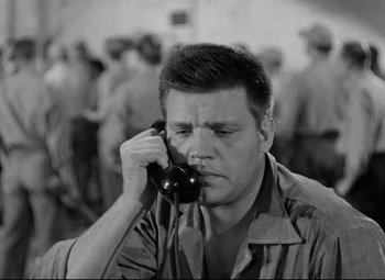 Movie still from “Riot in Cell Block 11” (1954), directed by Don Siegel – A black and white photo of a man talking on a phone; Close Up shot, High angle