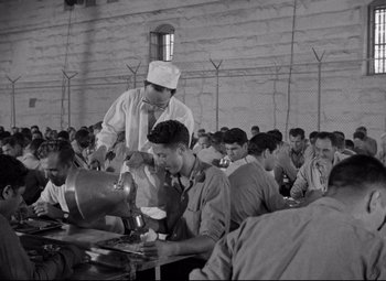 Movie still from “Riot in Cell Block 11” (1954), directed by Don Siegel – A group of people sitting around a table; Wide shot, High angle