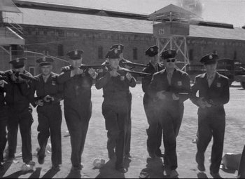 Movie still from “Riot in Cell Block 11” (1954), directed by Don Siegel – A black and white photo of a group of men in uniform; Wide shot, Low angle