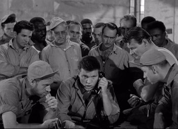 Movie still from “Riot in Cell Block 11” (1954), directed by Don Siegel – A group of men standing next to each other in a room; Medium shot, High angle