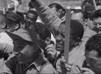 Movie still from “Riot in Cell Block 11” (1954), directed by Don Siegel – Black and white photograph of a group of men in a crowd; Medium shot, High angle