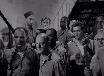 Movie still from “Riot in Cell Block 11” (1954), directed by Don Siegel – Black and white photograph of a group of men in military uniforms; Medium shot, High angle