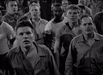 Movie still from “Riot in Cell Block 11” (1954), directed by Don Siegel – Black and white photograph of a group of men; Medium shot, High angle