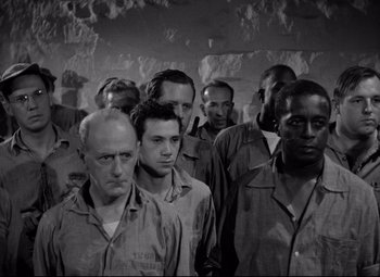 Movie still from “Riot in Cell Block 11” (1954), directed by Don Siegel – Black and white photograph of a group of men standing together; Medium shot, High angle