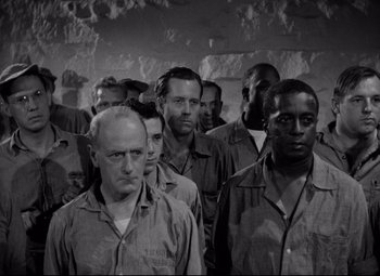 Movie still from “Riot in Cell Block 11” (1954), directed by Don Siegel – A group of men standing next to each other in a room; Medium shot, High angle