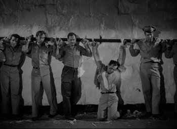 Movie still from “Riot in Cell Block 11” (1954), directed by Don Siegel – A black and white photo of a group of men holding guns; Wide shot, Low angle