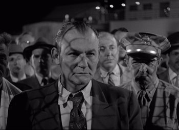 Movie still from “Riot in Cell Block 11” (1954), directed by Don Siegel – Black and white photograph of men in suits and ties; Medium shot, Low angle