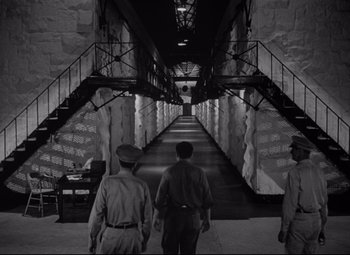 Movie still from “Riot in Cell Block 11” (1954), directed by Don Siegel – Three men are walking down a long staircase; Extreme Wide shot, High angle