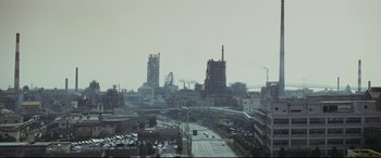 Movie still from “Ritual” (2000), directed by Hideaki Anno – A view of a large industrial area from a window; Extreme Wide shot, High angle