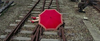 Movie still from “Ritual” (2000), directed by Hideaki Anno – A woman laying on the ground with an open umbrella; Wide shot, Overhead angle