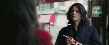 Movie still from “Ritual” (2000), directed by Hideaki Anno – A man holding a cigarette in his hand; Close Up shot, Over the shoulder angle