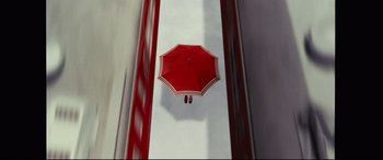 Movie still from “Ritual” (2000), directed by Hideaki Anno – An upside - down red umbrella floating on top of a building; Extreme Wide shot, Overhead angle