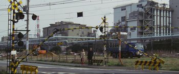 Movie still from “Ritual” (2000), directed by Hideaki Anno – Two people standing on the side of the road; Extreme Wide shot, Low angle