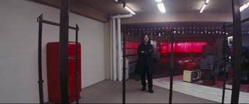 Movie still from “Ritual” (2000), directed by Hideaki Anno – A man standing in a room with red lights in the background; Wide shot, Low angle