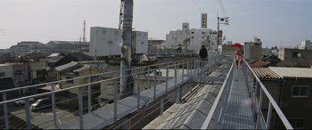 Movie still from “Ritual” (2000), directed by Hideaki Anno – A person is standing on a bridge over a river; Extreme Wide shot, Low angle