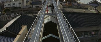 Movie still from “Ritual” (2000), directed by Hideaki Anno – Two people are walking on a bridge over a river; Extreme Wide shot, Overhead angle